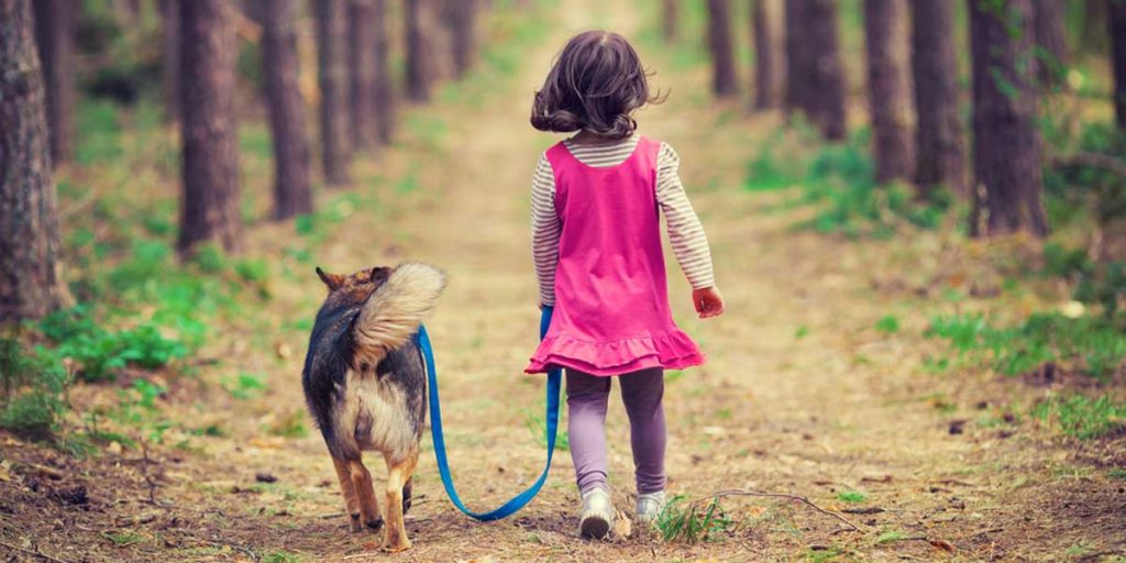 Picture of girl walking a dog down a path