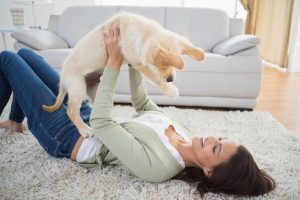 Picture of a woman on a rug holding up a puppy