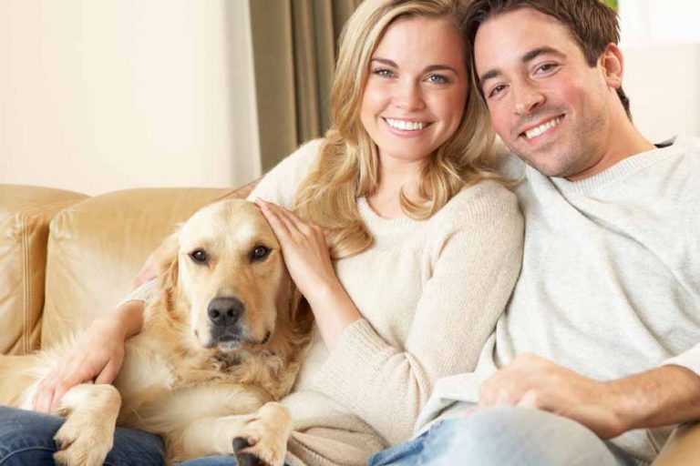 Picture of husband and wife on the sofa with a Golden Retriever