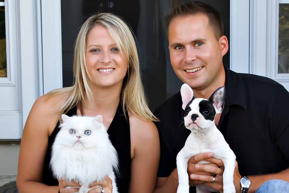Picture of man and woman holding dog and cat