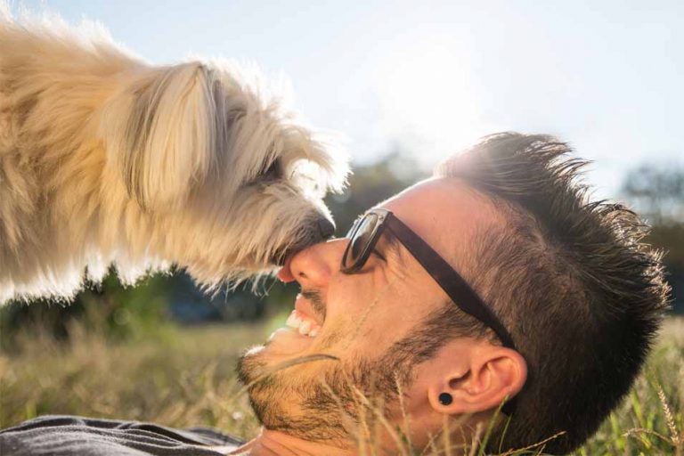 Picture of a dog licking a mans face outside