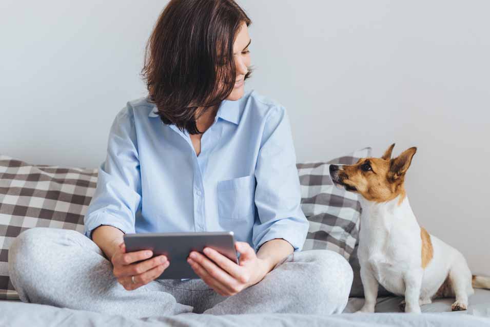Picture of dog looking at a woman that's sitting on the bed