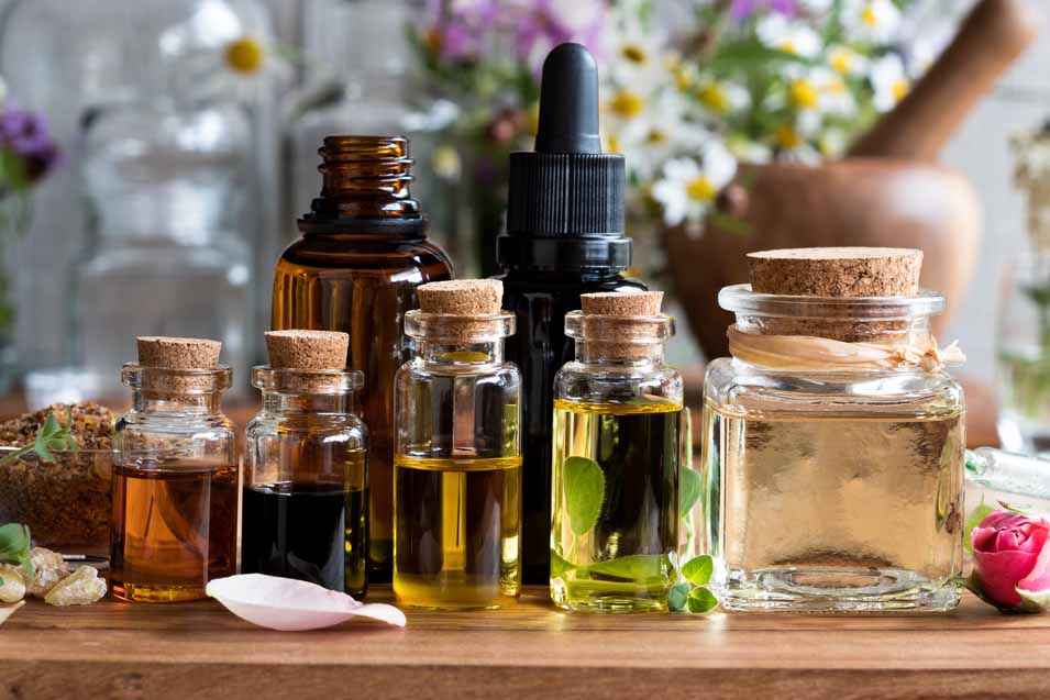 Picture of essential oils, with herbs and flowers in the background