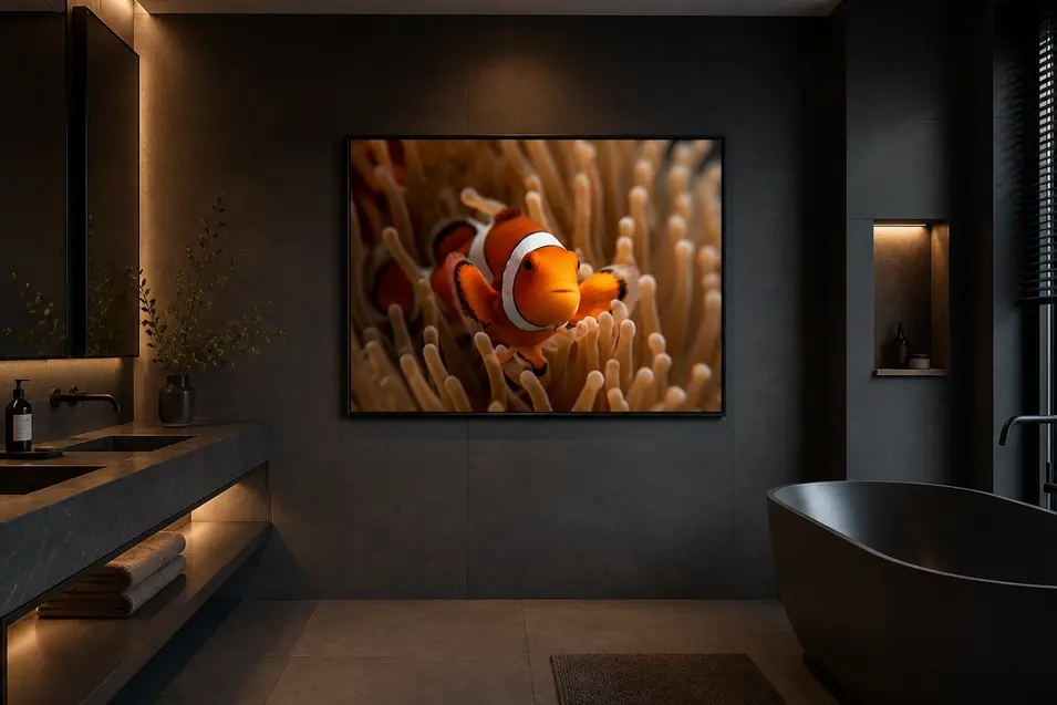 Dark luxury bathroom with charcoal stone, warm ambient lighting, a freestanding black tub, and a large framed clownfish artwork as the focal point.