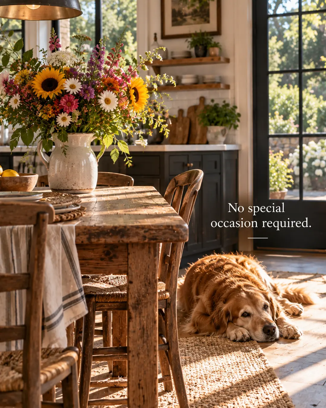 A Golden Retriever relaxes in a sunlit country kitchen beside a vibrant bouquet of wildflowers and the simple message, “No special occasion required.”